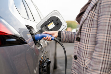 Midsection of woman charging electric car