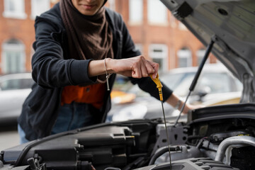 Woman checking oil in car engine - obrazy, fototapety, plakaty