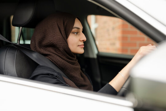 Young woman wearing hijab driving car