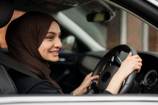 Young woman wearing hijab driving car