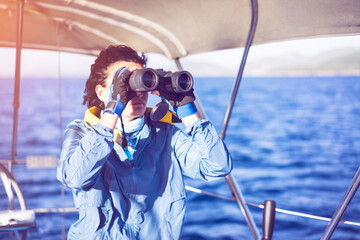 Young woman sailing, looking with binoculars