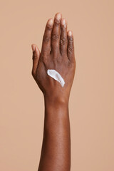 Woman hand with cream against beige background