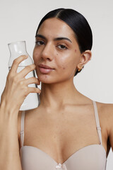 Portrait of young woman holding carafe with water against white background