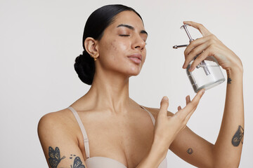 Portrait of young woman spraying face with water