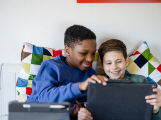 Boy friends (8-9, 10-11) using digital tablet at home - obrazy, fototapety, plakaty
