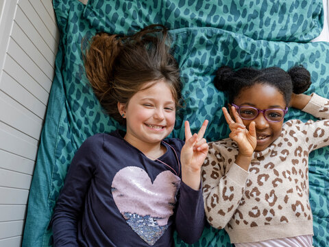 Portrait of girl friends (6-7) doing peace sign
