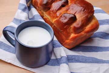 Fresh bread and a blue cup of milk on a towel