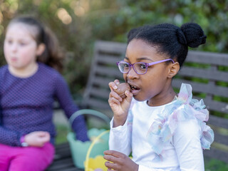 Girl friends (6-7) eating Easter chocolate eggs