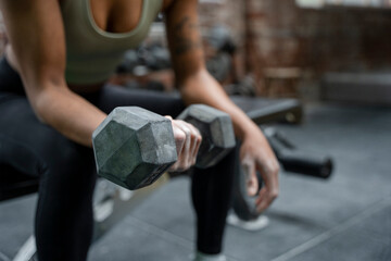 Woman holding dumbbell during weight training on gym - Powered by Adobe