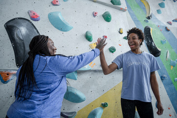 Mother and daughter giving high-five in front of climbing wall