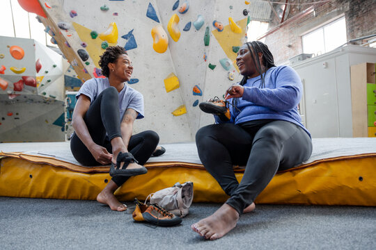Mother and daughter putting on climbing shoes while sitting on mattress