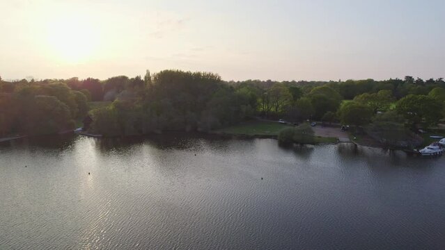 Aerial pan over Wroxham Broad, a body of water in the heart of the Norfolk Broads and the sailing club captured at sunset