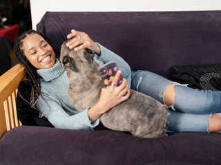 Woman embracing French Bulldog on sofa at home