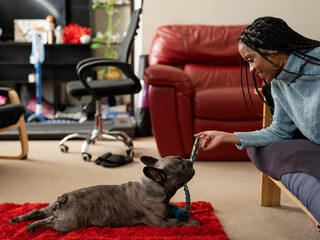 Woman playing with French Bulldog in living room