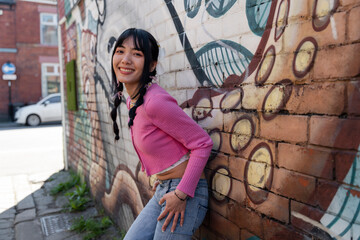 Portrait of young woman standing against graffiti wall