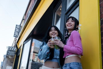 Young women standing in front of building with sweet drinks