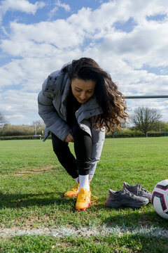 Young Woman Putting On Football Cleats