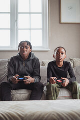 Brothers (10-11), (14-15) playing video game at home