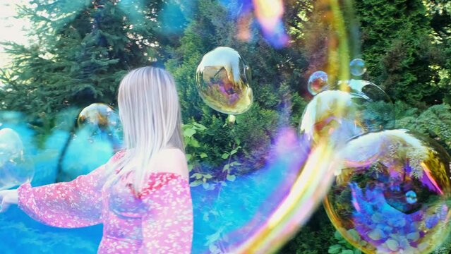a woman in a red dress is playing with soap bubbles on the green lawn
