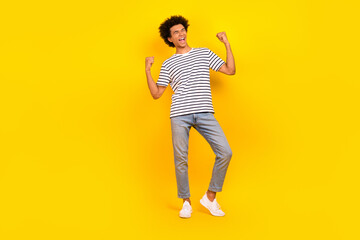 Full body cadre of overjoyed funny youngster man raised fists up triumphant approved job applicant isolated on yellow color background