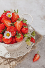 Świeże truskawki w metalowym sitku na jasnym tle.