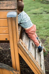 Little boy playing and climbing at the playground in summer