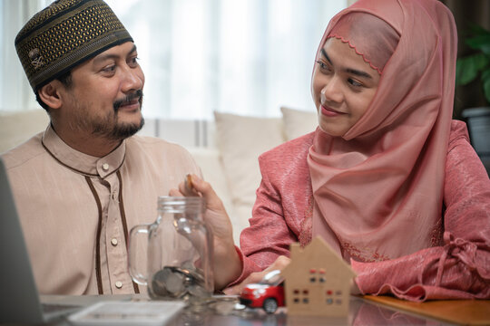Asian muslim family hands putting coins into glass jar, savings income and finance concept.