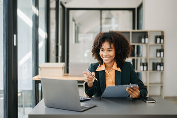 Fototapeta premium Confident business expert attractive smiling young woman typing laptop ang holding digital tablet on desk in office.