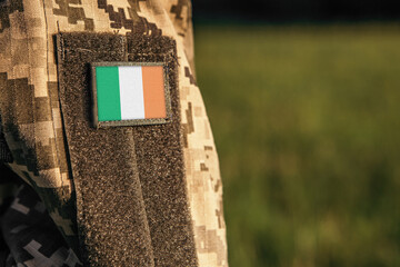Close up millitary woman or man shoulder arm sleeve with Ireland flag patch. Troops army, soldier camouflage uniform. Armed Forces, empty copy space for text
