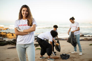 Fototapeta premium Happy young diverse people volunteers in t-shirts and asian lady with garbage bags clean up trash