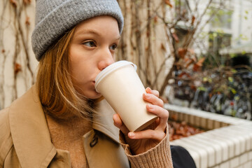 Young woman drinking coffee while sitting outdoors at street