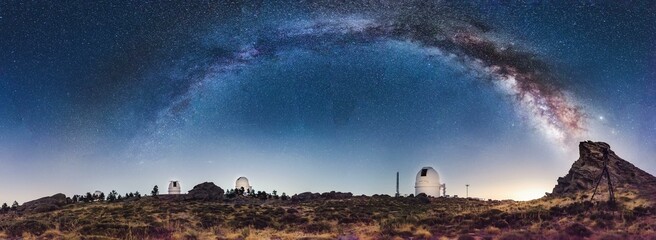 astronomical observatory domes observing the starry night sky with the full arc of the milky way