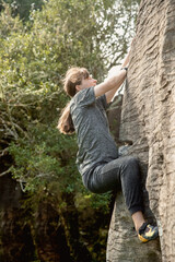 young active teen girl doing outdoor rock climbing bouldering on natural cliff. High quality photo