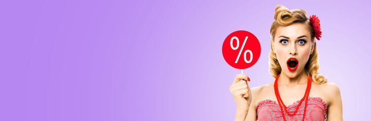 Face portrait of excited shocked woman with open mouth, hold red signboard with % sign. Blond pin up retro style girl. Isolated light purple background. Sale ad concept. Wide image.