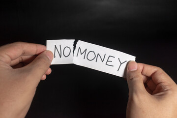 a young man hand holding a paper reads no money sign and rip the no text. isolated black background