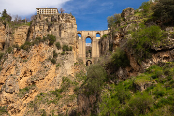 Fototapeta na wymiar The famous bridge with arched vaults between the rocks of the gorge on a sunny day. Landmark of the city of Ronda, Andalusia, Spain