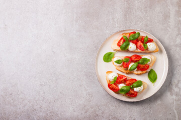 Tomato, basil and mozzarella cheese fresh made caprese bruschetta. Italian tapas, antipasti with vegetables, herbs and oil on grilled ciabatta and baguette bread. Open sandwich.