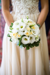 Obraz na płótnie Canvas White wedding bouquet in bride's hands, close up