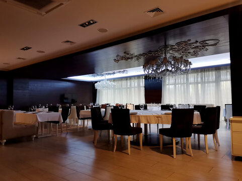 Spacious restaurant hall interior detail with tables, chairs and chandelier