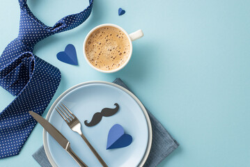 A lovely Father's Day table setting with a top view flat lay of plates, cup of coffee, napkin, necktie, mustaches, and hearts on a pastel blue backdrop with empty space for text