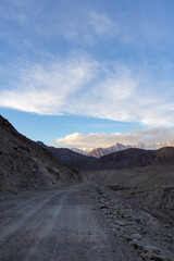 Mountain road with snow-covered mountains in the distance in Ladakh region, India