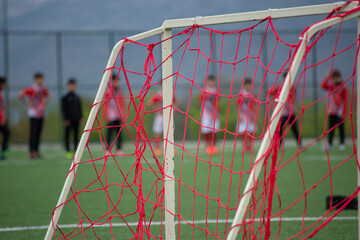 Focused on soccer goal nets..Young soccer players training on the soccer field in the background.