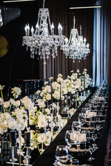 Banquet decoration composition flowers, candles, candlesticks in hall restaurant. Luxury wedding reception. Table setting, setup. Trendy black rich decor. Birthday, baptism, event. Details interior.