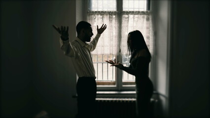 Silhouette of couple fighting each other, arguing and yelling at one another. Young man and woman shouting in anger. Candid behind closed doors