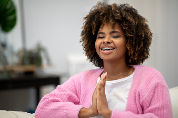 Closeup of happy black woman holding hands in namaste gesture