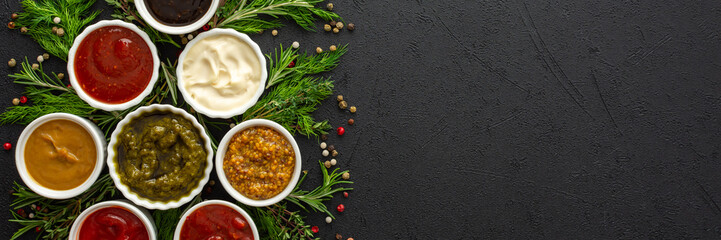 Different types of sauces in bowls with seasonings banner, rosemary and dill, thyme and and peppercorns, top view, copy space
