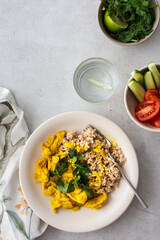 Healthy lunches, brown rice with chicken with turmeric and curry seasoning, fresh vegetables and herbs, water with lemon, top view on the table