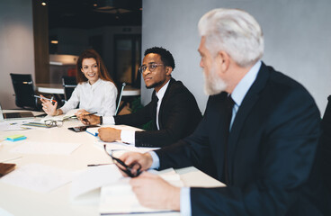 Group of diverse colleagues sitting at table in office with documents
