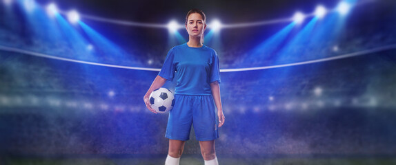 Fototapeta na wymiar Portrait of young female soccer player with soccer ball standing in a big stadium.