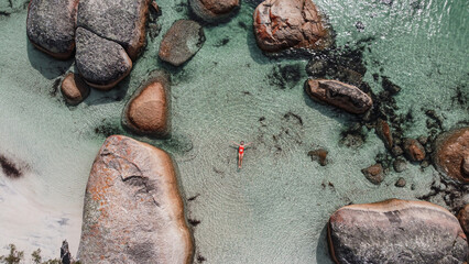 Aerial picture of a girl swimming in a fairy pool in Albany, Australia. Shallow and transparent water. Drone picture. Swimming in paradise in a lagoon between rocks. - obrazy, fototapety, plakaty